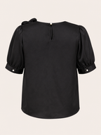 Black blouse with puff sleeves on a beige background