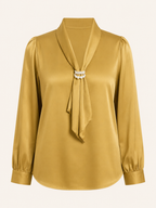 Gold blouse with a pearl necklace on a white background