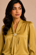 Woman wearing a mustard yellow satin blouse with a beige background