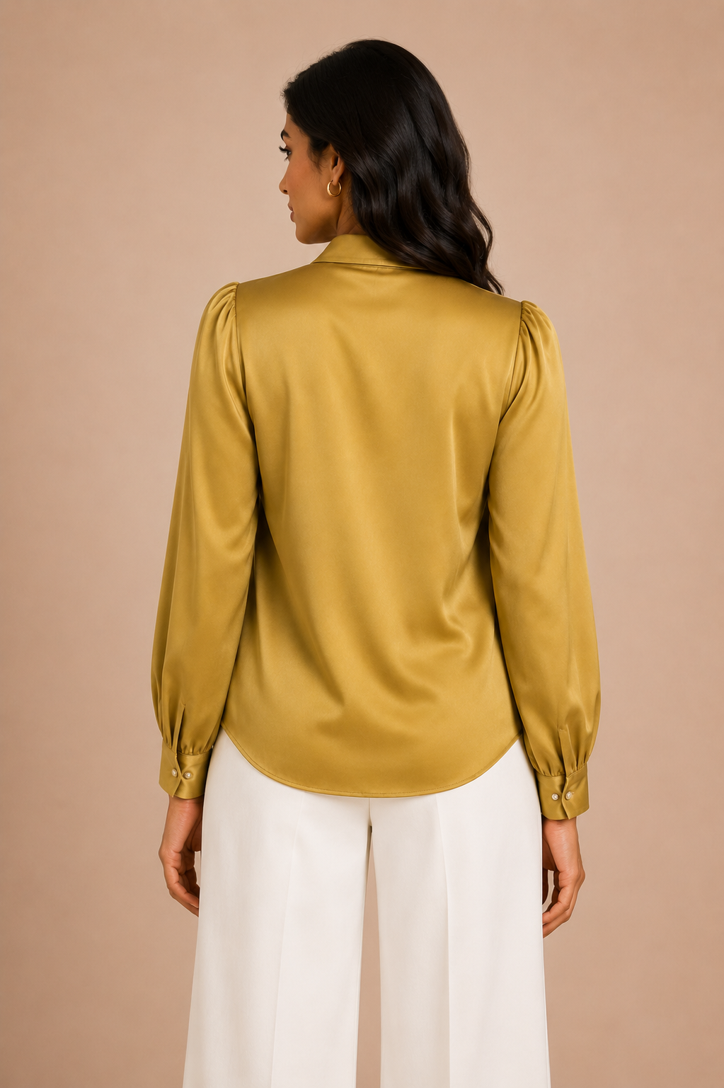 Woman wearing a mustard yellow blouse and white pants against a beige background