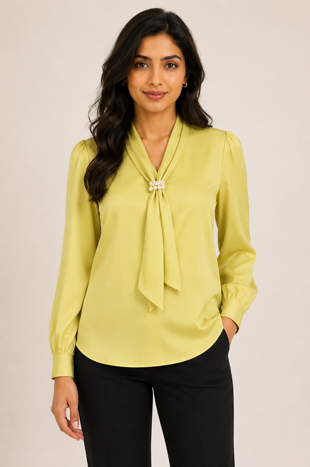 Woman wearing a light green blouse with a tie detail against a plain background