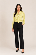 Woman wearing a yellow blouse and black pants on a beige background
