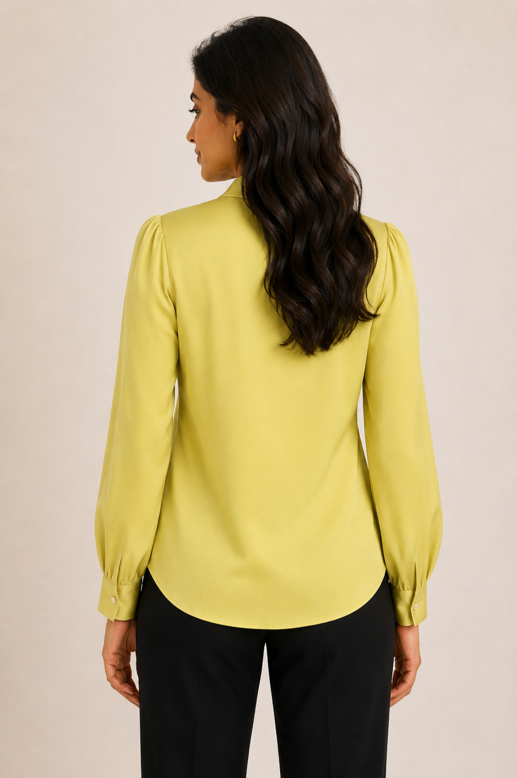 Woman wearing a light green blouse with long sleeves against a beige background
