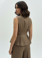 Woman wearing a brown peplum top and pants on a white background