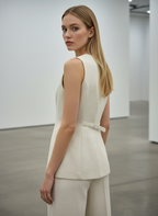 Woman wearing a white sleeveless top and pants in a minimalistic setting