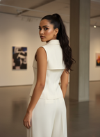 Woman in a white outfit standing in an art gallery.