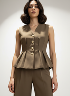 Woman wearing a brown peplum top with buttons on a plain background