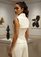 Woman in a white outfit standing in an art gallery with sculptures and paintings on the walls.