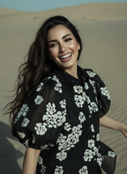 Woman in a black floral dress standing in sand dunes
