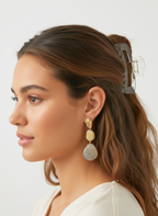 Woman wearing gold and silver earrings with a neutral background