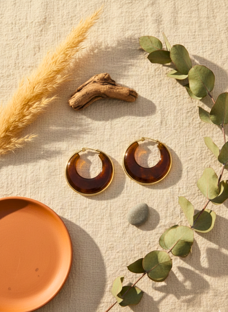 Hoop earrings with tortoiseshell design on a textured surface with natural elements.