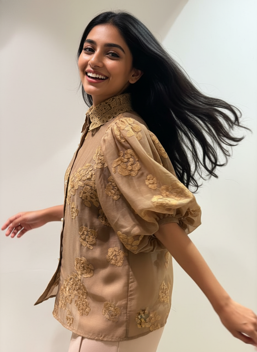 Woman wearing a beige embroidered blouse against a plain background