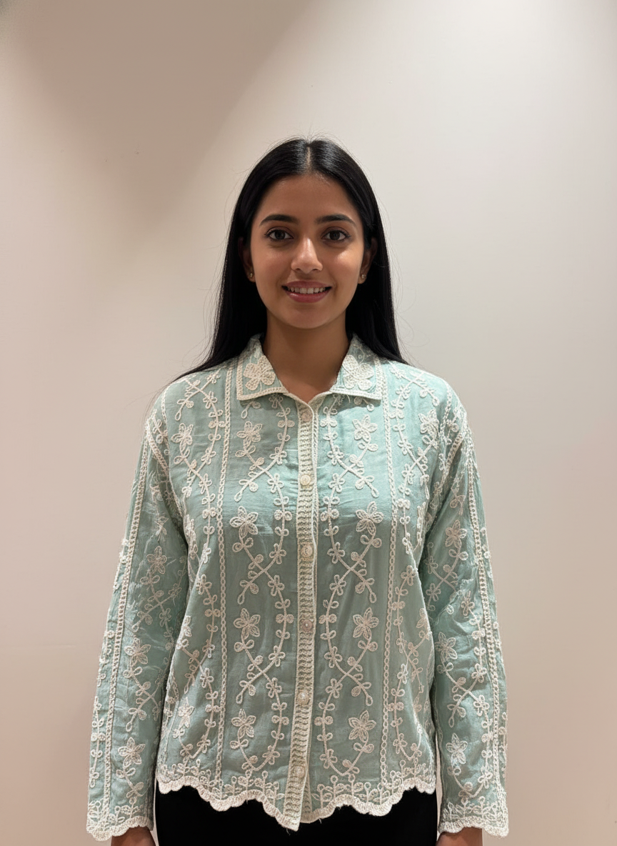 Woman wearing a light blue lace blouse against a plain background