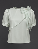 Light gray blouse with sheer sleeves and floral details on a dark background