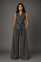 Woman wearing a gray pinstripe suit with wide-leg pants against a gray background