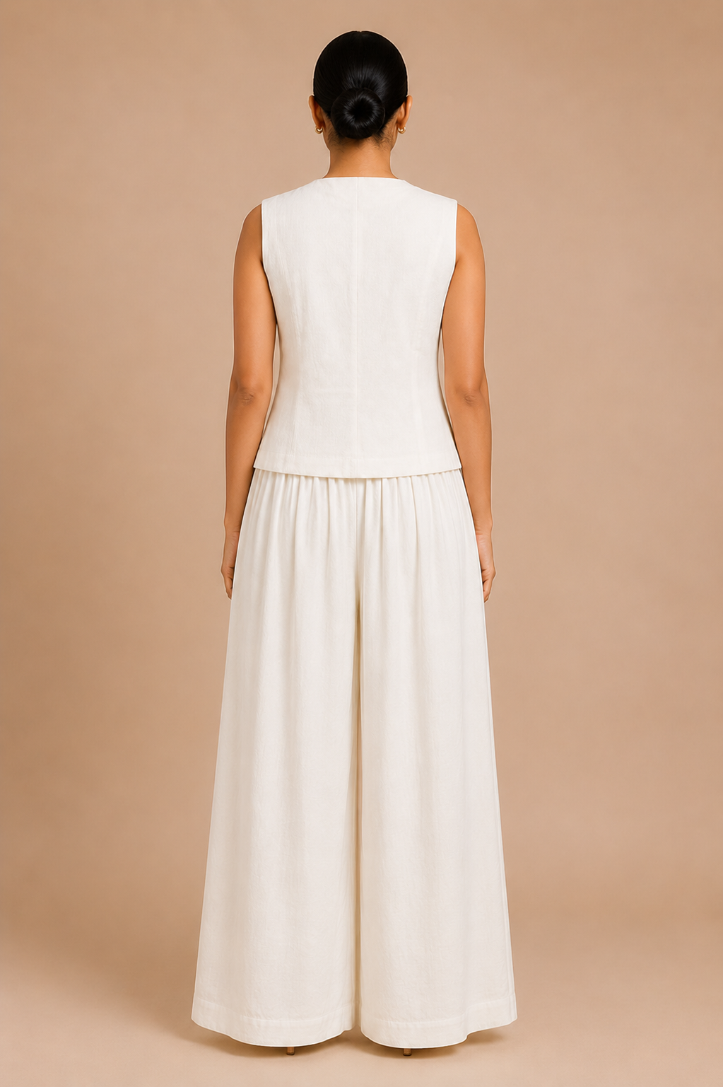 Woman wearing a white sleeveless top and wide-leg pants on a beige background