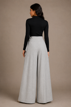 Woman wearing a black top and light gray wide-leg pants against a beige background