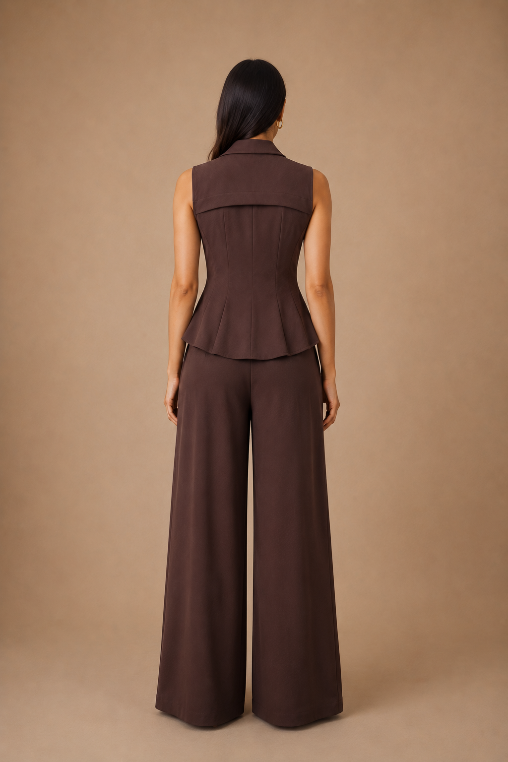 Woman wearing a brown sleeveless top and wide-leg pants against a beige background