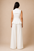 Woman wearing a white sleeveless top and wide-leg pants against a beige background