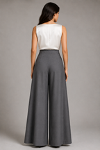 Woman wearing a white sleeveless top and gray wide-leg pants on a plain background