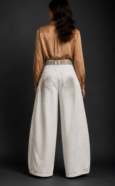 Person wearing a beige blouse and white wide-leg pants against a black background