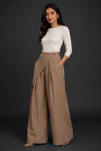 Woman wearing a white top and beige wide-leg pants against a dark background