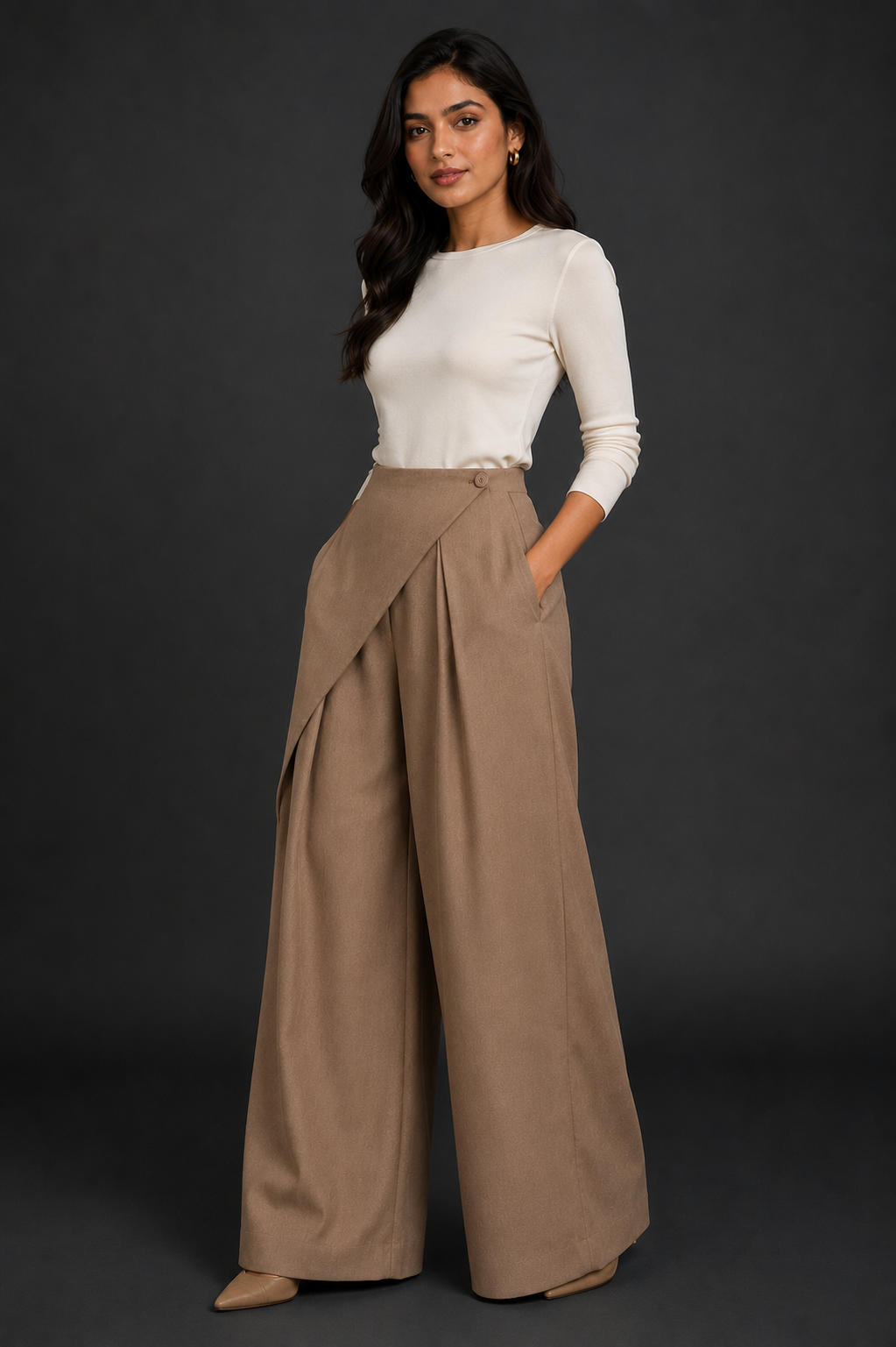 Woman wearing a white top and beige wide-leg pants against a dark background