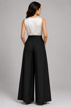 Woman wearing a white sleeveless top and black wide-leg pants on a gray background