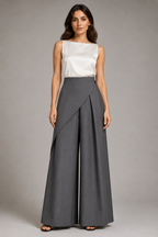 Woman wearing a white top and gray wide-leg pants on a plain background