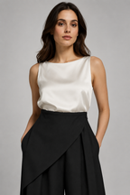 Woman wearing a white sleeveless top and black skirt against a gray background