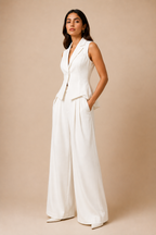 Woman wearing a white sleeveless jumpsuit against a beige background