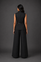 Person wearing a black sleeveless top and wide-leg pants against a gray background