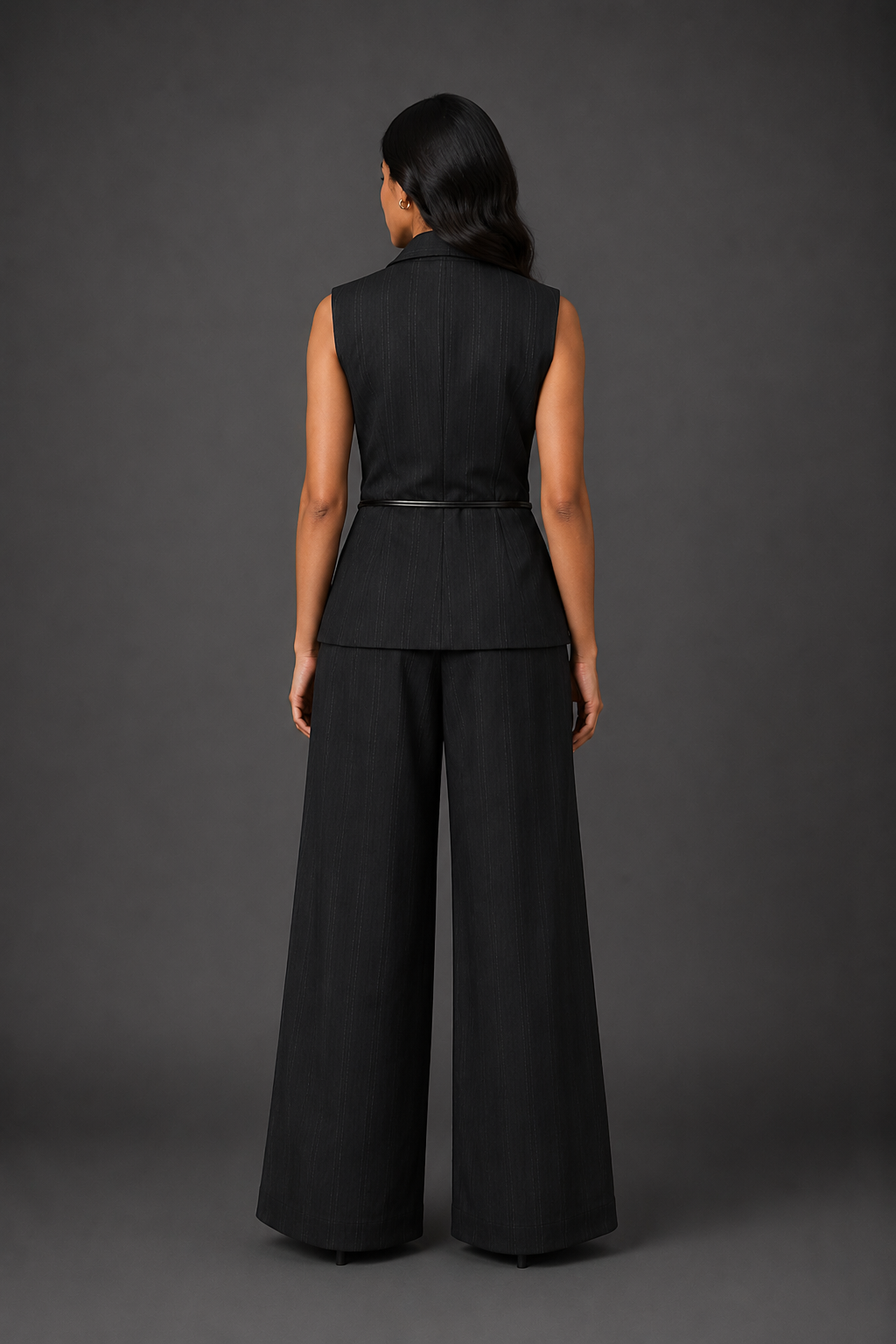 Person wearing a black sleeveless top and wide-leg pants against a gray background
