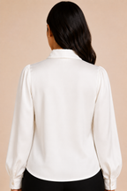 White blouse with long sleeves worn by a person on a beige background