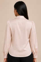 Woman wearing a light pink blouse with long sleeves against a beige background