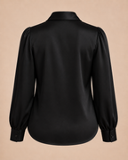 Black blouse with puff sleeves on a beige background