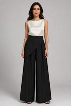 Woman wearing a white sleeveless top and black wide-leg pants on a gray background