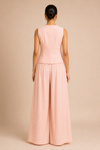 Person wearing a pink sleeveless top and wide-leg pants on a beige background