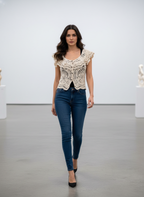 Woman wearing a lace top and blue jeans against a plain background