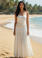 Woman in a white dress standing on a beach with palm trees in the background
