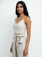 Woman wearing a beige sleeveless top and wide-leg pants against a white background
