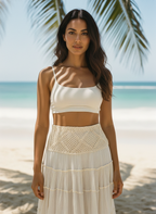 Woman in a white top and beige skirt standing on a beach with palm trees in the background