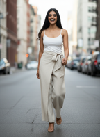 Woman walking on a city street wearing a white top and beige pants.