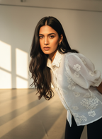 Woman wearing a white lace blouse in a softly lit room