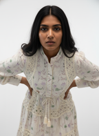 Woman wearing a white floral dress with lace details against a plain background