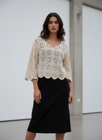 Woman wearing a white lace top and black skirt in a minimalistic setting