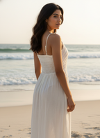 Woman in a white dress standing on a beach with ocean waves in the background